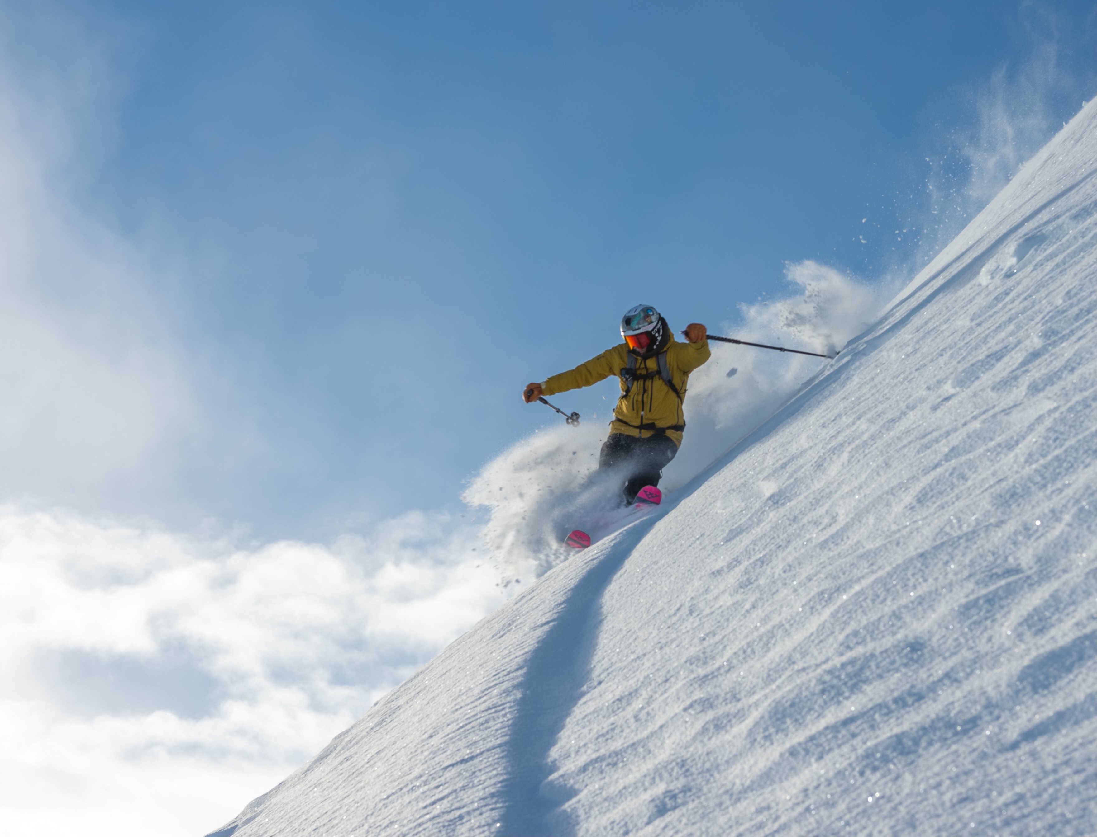 Skier slashing a deep powder turn on a bluebird day