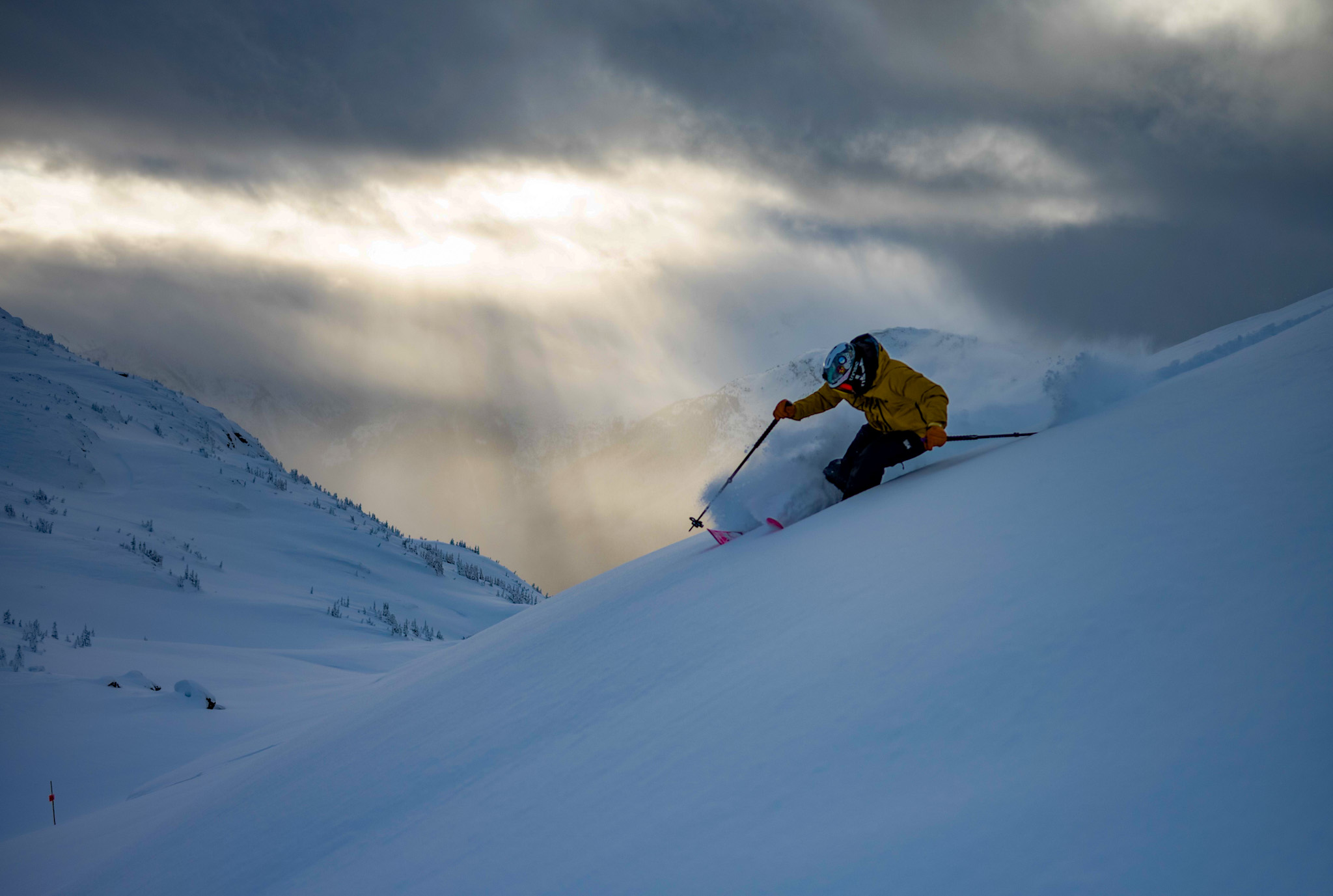 Skier carving through backcountry powder under storm light
